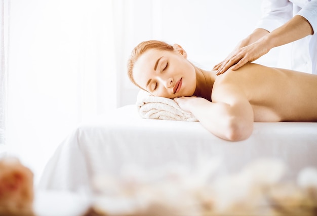 Belle femme profitant d'un massage du dos les yeux fermés dans un centre de spa ensoleillé Concept de traitement relaxant en médecine