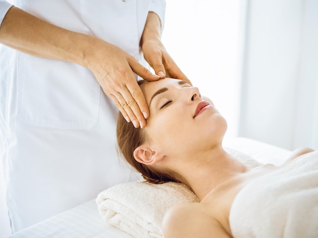 Belle femme profitant d'un massage facial avec les yeux fermés dans le centre de spa. Détendez-vous le concept de traitement en médecine.