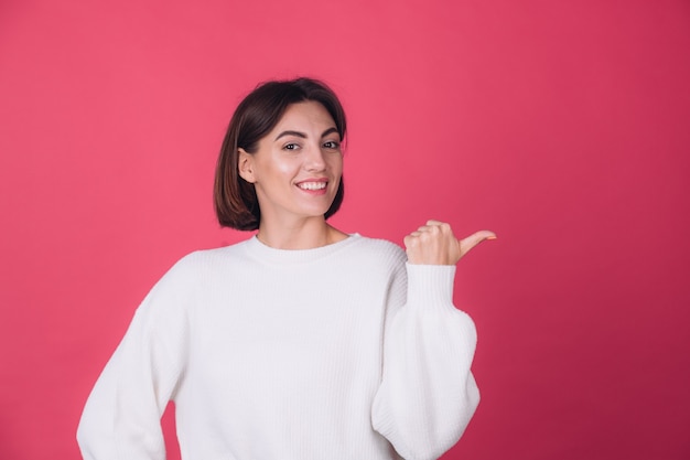 Belle femme en pull blanc décontracté sur mur rouge