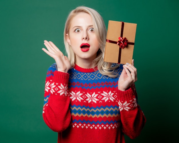 Belle femme en pull de Noël avec boîte-cadeau