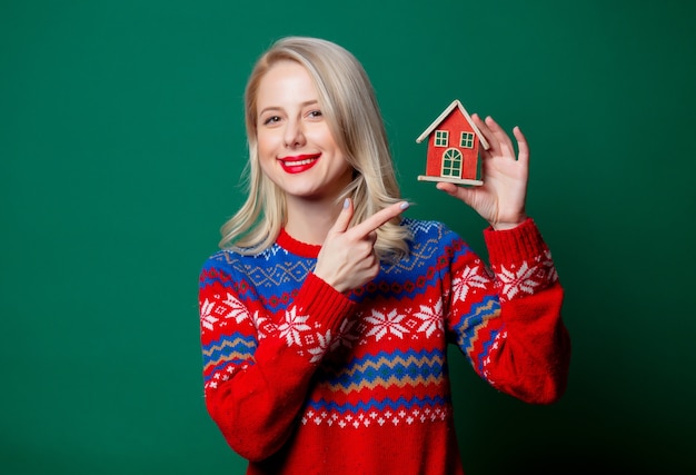 Belle femme en pull de Noël avec maison de jouet