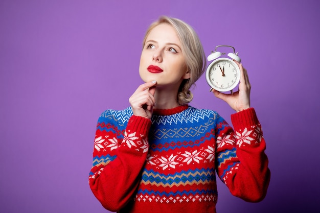 Belle femme en pull de Noël avec réveil