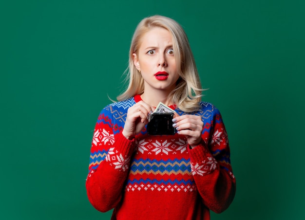 Belle femme en pull de Noël tient un sac à main avec de l'argent