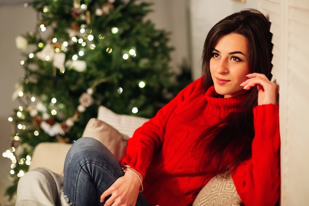 Belle femme avec un pull rouge sur le canapé