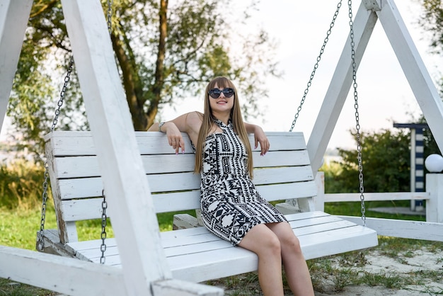 Belle femme qui respire sur une balançoire en bois blanc en été