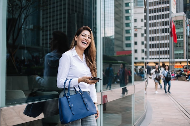 Belle femme qui rit avec le téléphone à la main