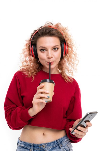 Belle femme de race blanche aux cheveux blonds bouclés boit du café et des sourires