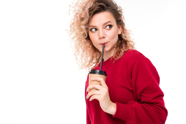 Belle femme de race blanche avec des cheveux blonds bouclés boit du café isolé sur fond blanc