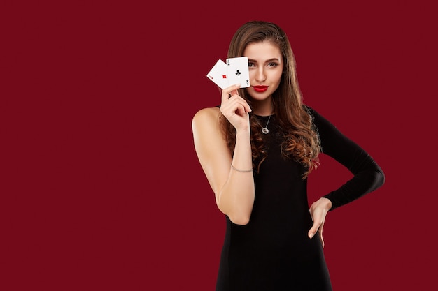 Belle femme de race blanche en robe noire avec des cartes de poker jouant au casino