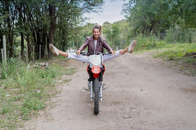 Belle femme rasta chevauchant une moto et soulevant les deux jambes