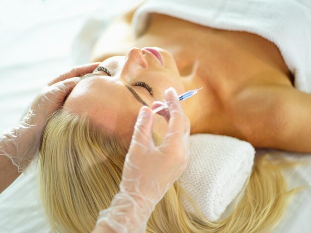 Belle femme reçoit des injections faciales de beauté face à la cosmétologie esthétique par injection vieillissante