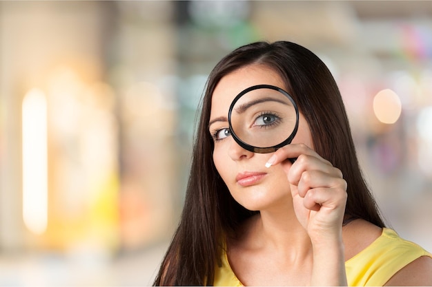 Belle femme regardant à travers une loupe