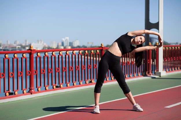 Belle femme de remise en forme qui s'étend sur la passerelle piétonne avant de s'entraîner. Espace pour le texte