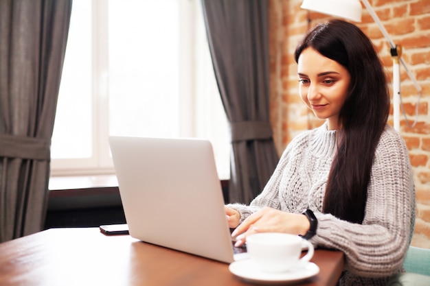 Belle femme, rester à la maison et travailler sur un ordinateur portable en ligne