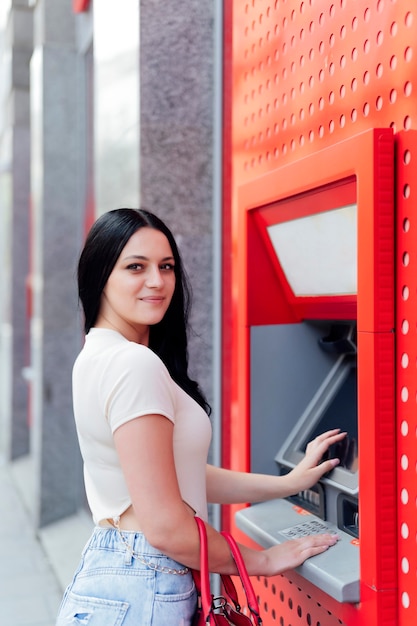 Belle femme retirant de l'argent du distributeur de billets.