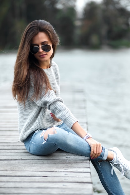 Belle femme de rêve assise sur la jetée au bord du lac.