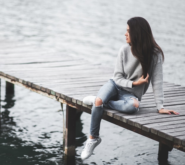 Belle femme de rêve assise sur la jetée au bord du lac.