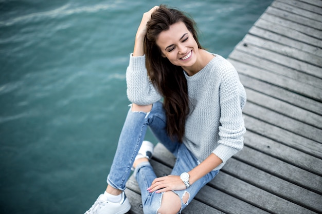 Belle femme de rêve assise sur la jetée au bord du lac.