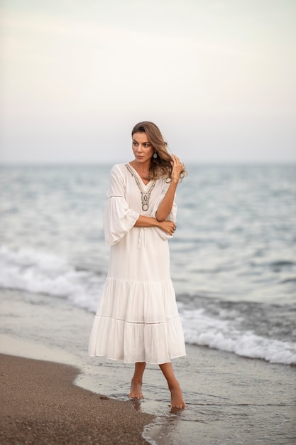 Belle femme en robe blanche au bord de la mer