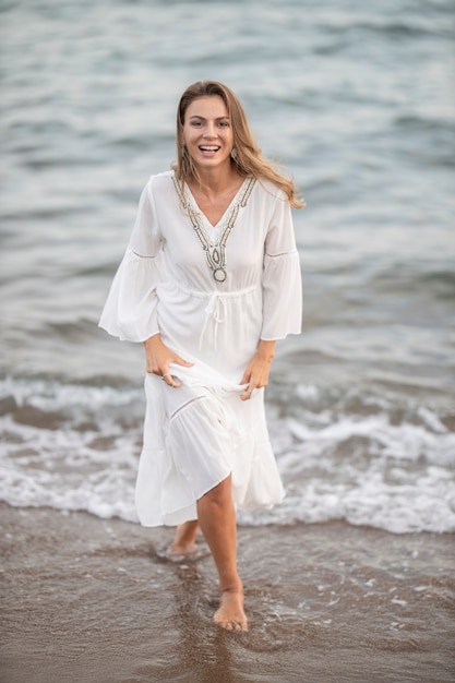 Belle femme en robe blanche au bord de la mer