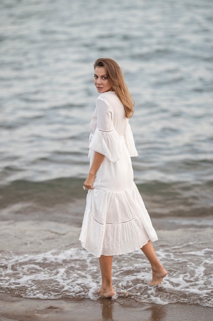Belle femme en robe blanche au bord de la mer