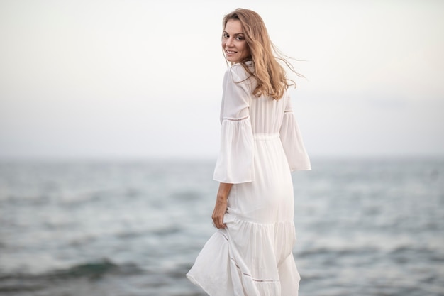 Belle femme en robe blanche au bord de la mer