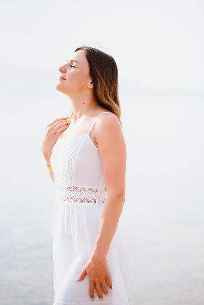 Belle femme en robe blanche marchant sur la plage