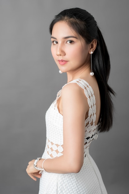 Belle femme en robe blanche portrait en studio, fond gris