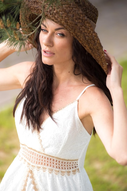 Belle femme en robe d'été blanche et chapeau de paille