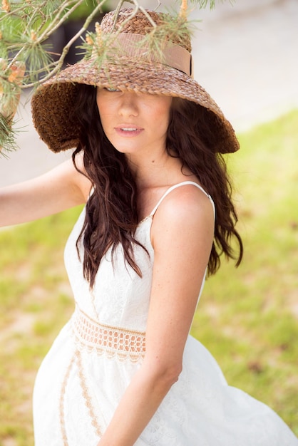 Belle femme en robe d'été blanche et chapeau de paille