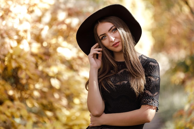 Belle femme en robe noire et chapeau en automne