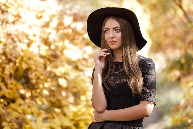 Belle femme en robe noire et chapeau en automne