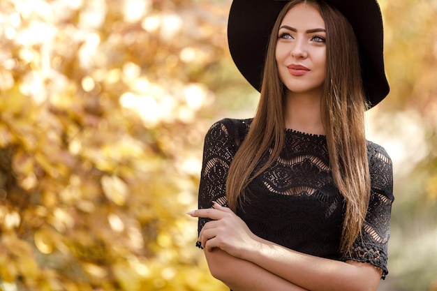 Belle femme en robe noire et chapeau en automne