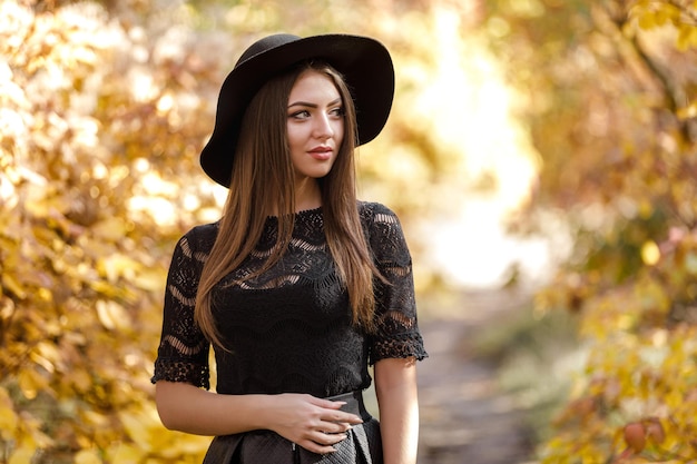 Belle femme en robe noire et chapeau en automne