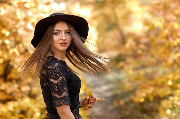 Belle femme en robe noire et chapeau en automne