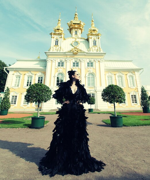 Belle femme en robe noire posant à côté du palais. Reine noire.