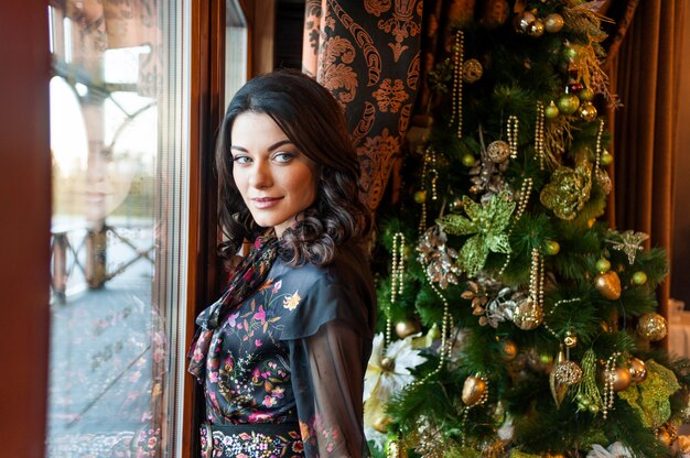 Belle femme en robe de soirée près de sapin de Noël