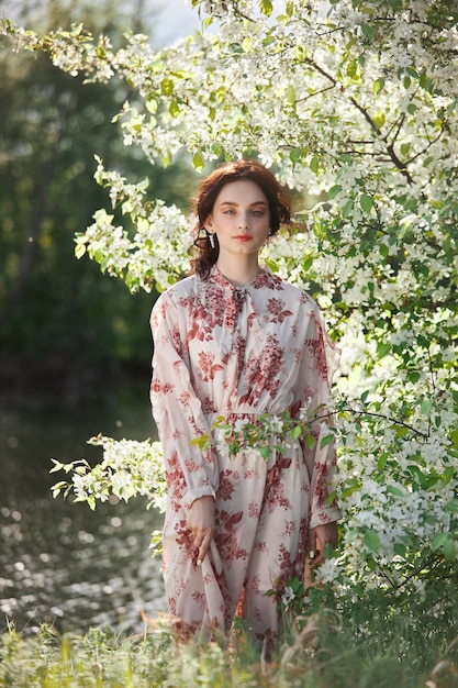 Belle femme romantique se dresse dans les branches du pommier en fleurs. Fille de portrait de printemps en fleurs pommier