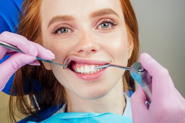 Belle femme rousse au gingembre est assise dans le fauteuil dentaire. Elle est venue voir le dentiste à la clinique.