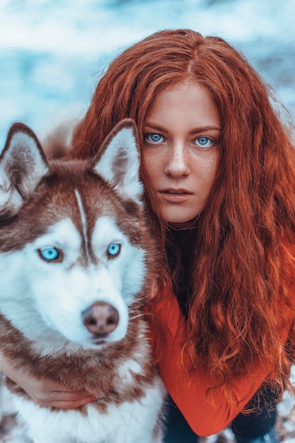 Photo belle femme rousse dans la neige avec un husky rouge