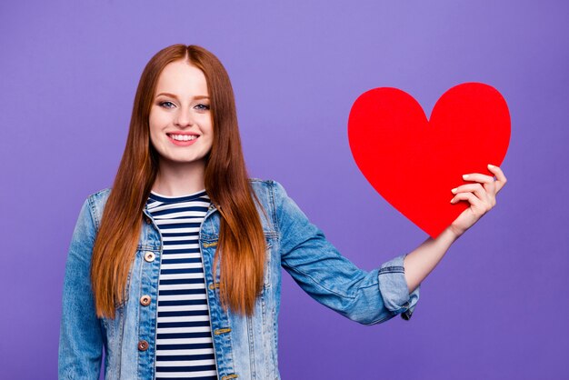 Photo belle femme rousse posant avec un grand coeur de papier