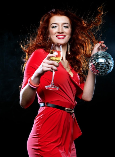 Belle femme rousse sexy avec un verre de vin blanc et une boule disco
