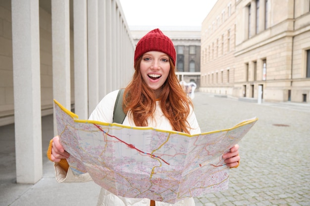 Belle femme rousse touriste avec carte de la ville explore les monuments historiques à pied autour