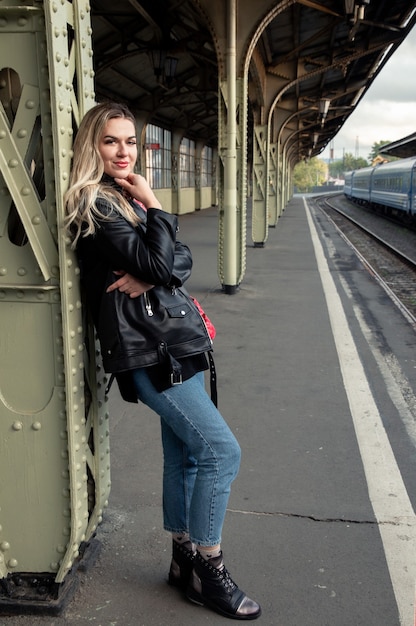 Belle femme s'appuyant sur un poteau sur le quai de la gare