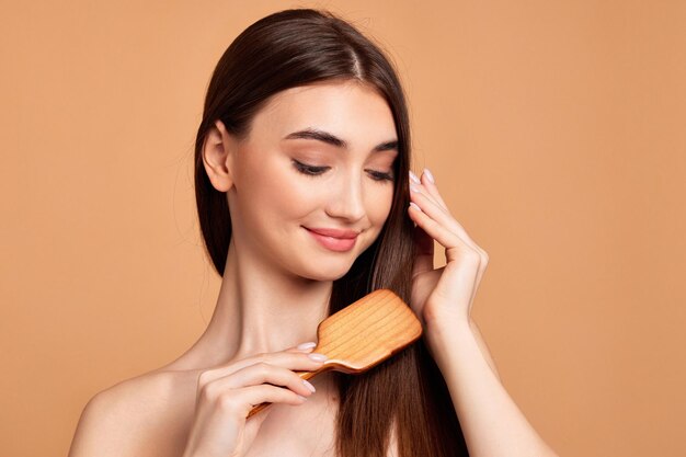 Belle femme se coiffe avec une brosse en bois