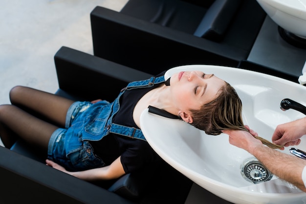 Belle femme se laver les cheveux dans un salon de beauté