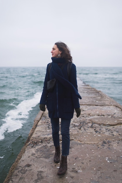 Une belle femme se promène sur la plage avec des mouettes en hiver.