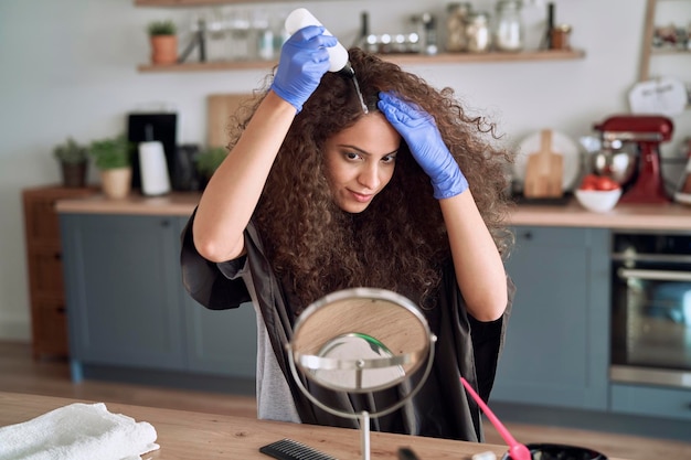 Une belle femme se teint les cheveux à la maison.