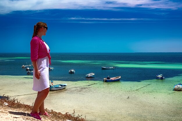 Une belle femme se tient sur les rives de la mer Méditerranée sur l'île de Djerba, Tunisie