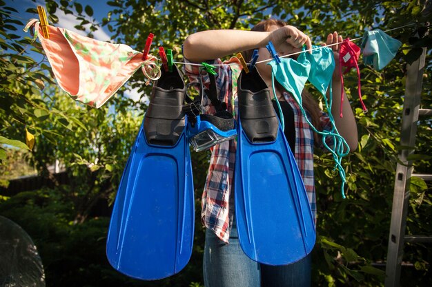 Belle femme séchant des palmes et un masque de plongée en apnée sur une corde à linge